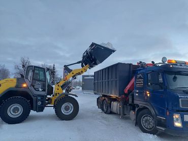 Aura-auto nostaa lunta kuorma-auton kyytiin